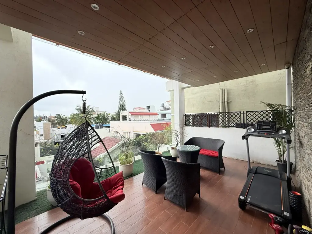 Modern Mirage rooftop terrace featuring a private treadmill, relaxing swing, and breakfast table with panoramic Bengaluru views