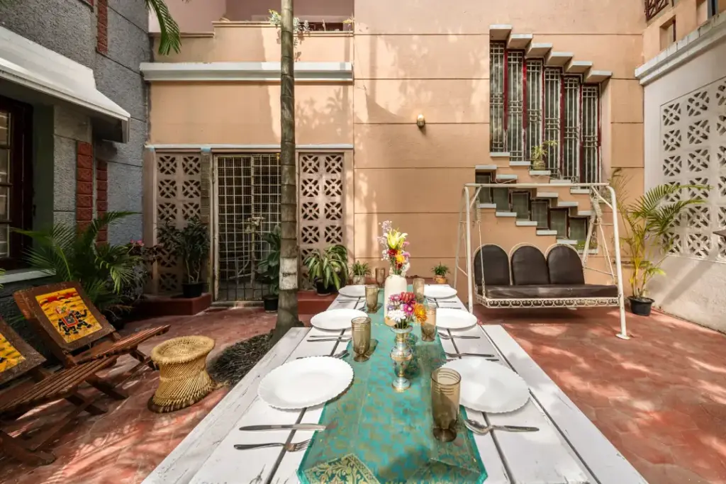 Outdoor garden dining area at Heritage Haven Spacez with a traditional wooden swing for relaxed family meals and evening tea