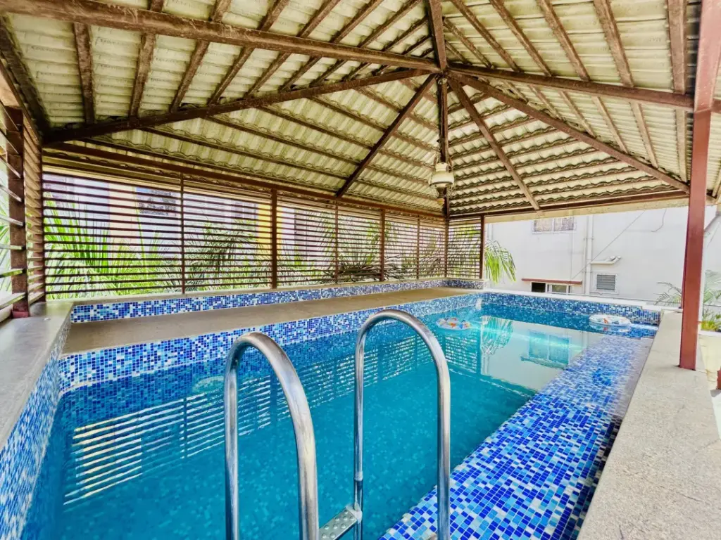 Private turquoise swimming pool at Lagoon Luxe Spacez Villa Bengaluru with luxury poolside loungers and tropical landscaping