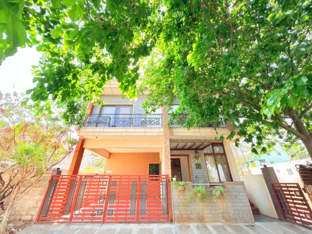 Exterior architectural view of Serene Springs by Spacez, showcasing a modern luxury villa design with a private pool, landscaped lawns, and contemporary glass facade in Bengaluru.