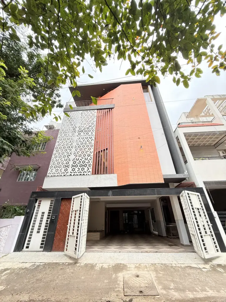 Exterior drone view of Urban Utopia, a premium managed villa in RR Nagar Bengaluru with a modern glass architecture, private swimming pool, and gated lawn for group celebrations.