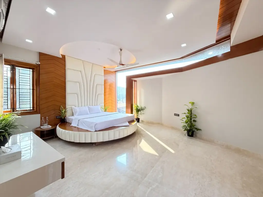 Modern luxury bedroom at Urban Utopia by Spacez, highlighting a plush king-size bed, warm ambient lighting, and large glass windows for a serene staycation in RR Nagar.