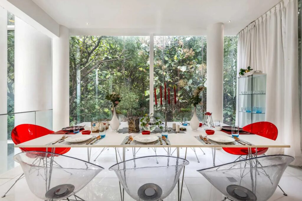 Modern open-concept dining area at Crystal Hall by Spacez, showing a large contemporary table setup for a group party, surrounded by all-glass architecture and scenic outdoor nature views.