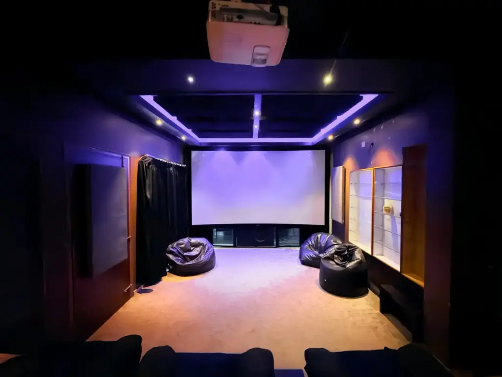 Ultra-luxury private home theater at Serene Springs by Spacez, featuring a large 4K projector screen, premium acoustic wall paneling, and plush recliner seating for a cinematic IPL watch party.