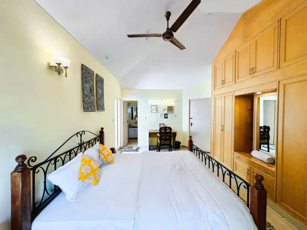 Large master bedroom at Vintage Haven with premium wooden interiors, high ceilings, and ambient lighting, designed for a peaceful staycation in the heart of Bengaluru's Indiranagar.