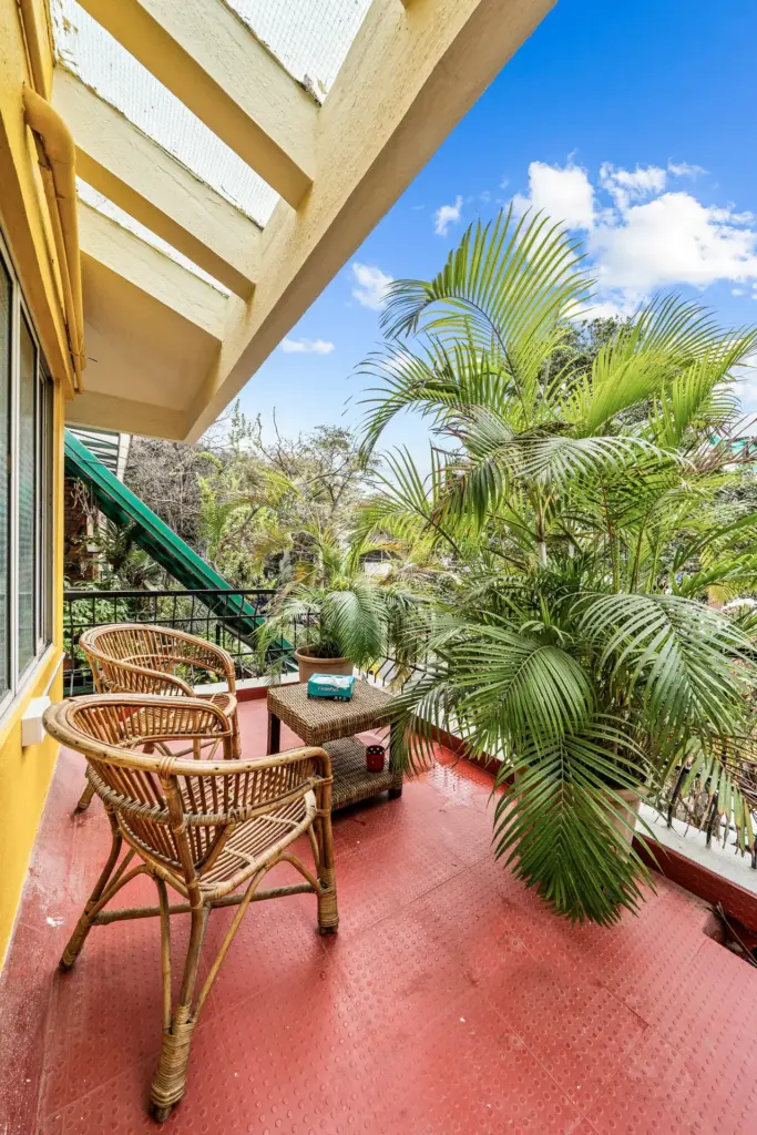 Private balcony at Vintage Haven villa overlooking the lush green canopy of Indiranagar, featuring a traditional swing and seating for a relaxed outdoor match-day experience.